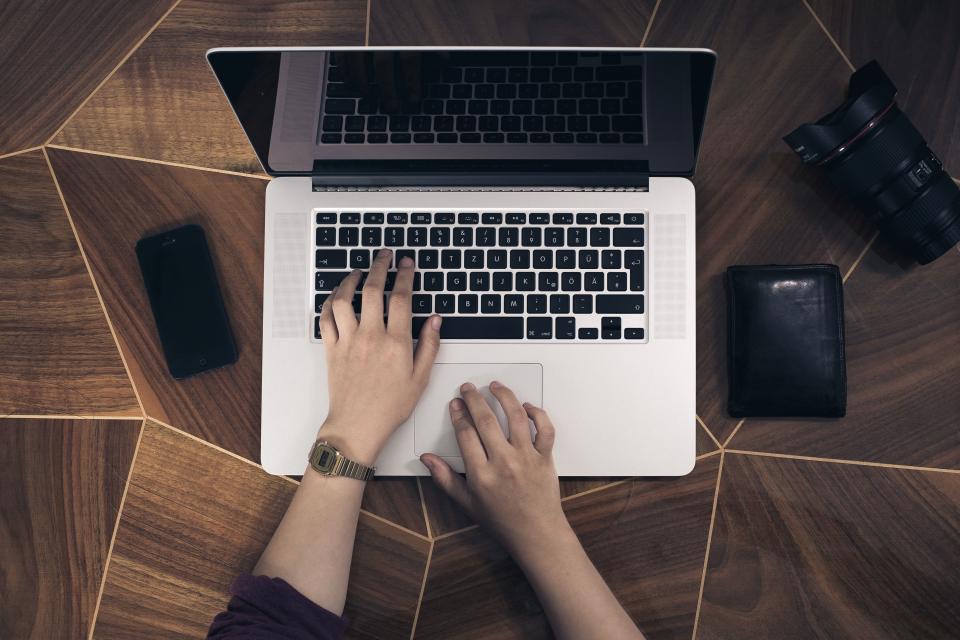 Hands typing on a laptop